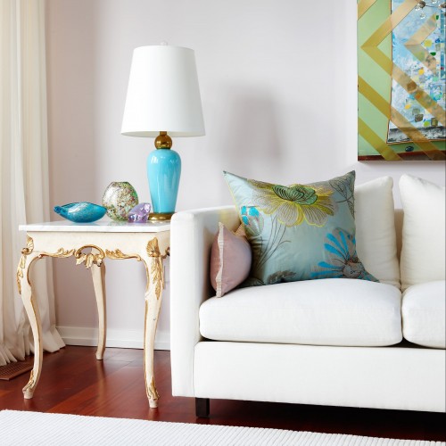 White couch with side table beside it and white rug on dark hardwood floors