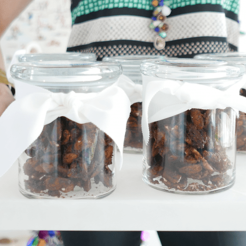 Sarah Richardson holding a tray of spiced nuts in jars wrapped in white ribbon